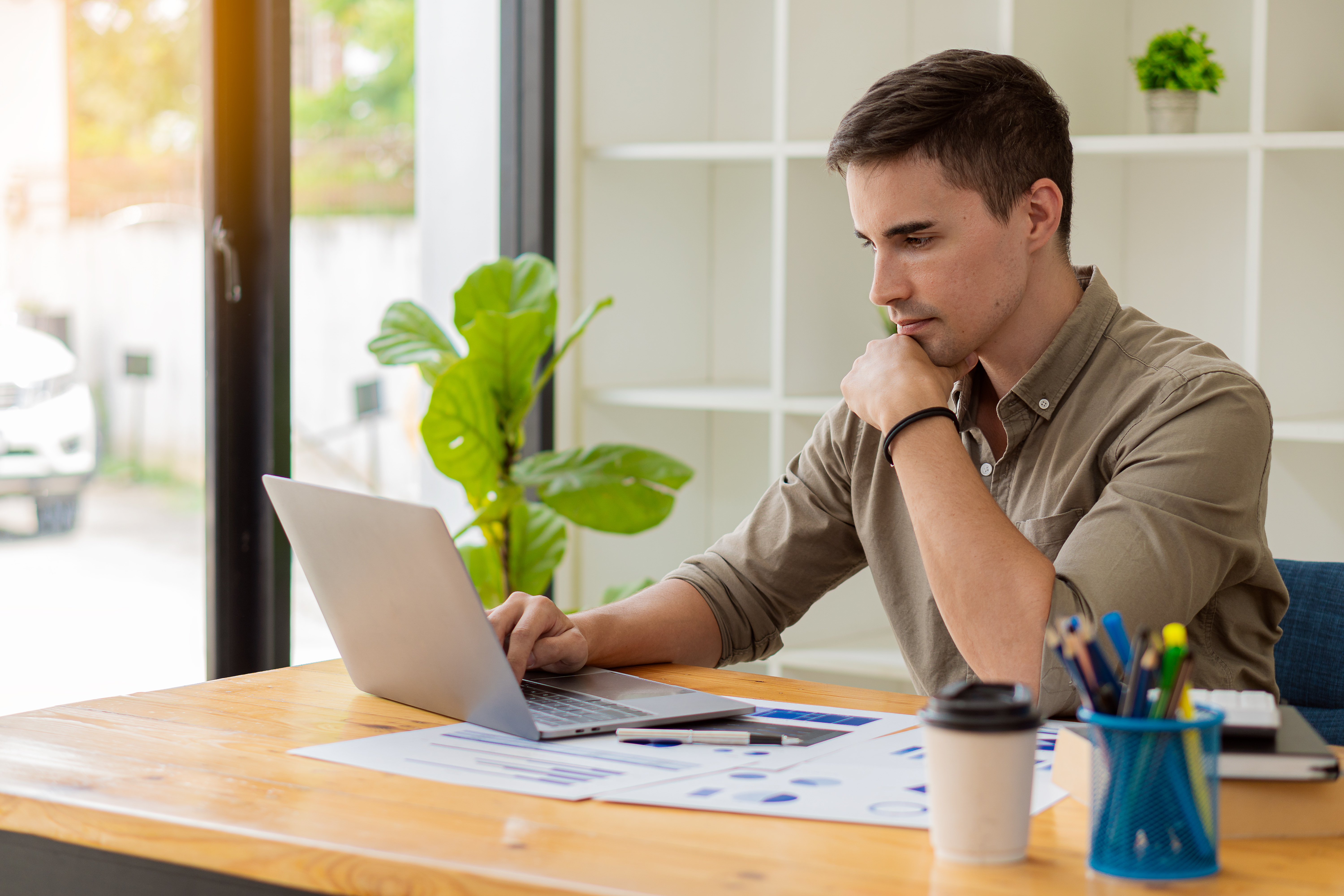 Man uses laptop and sits at a table.