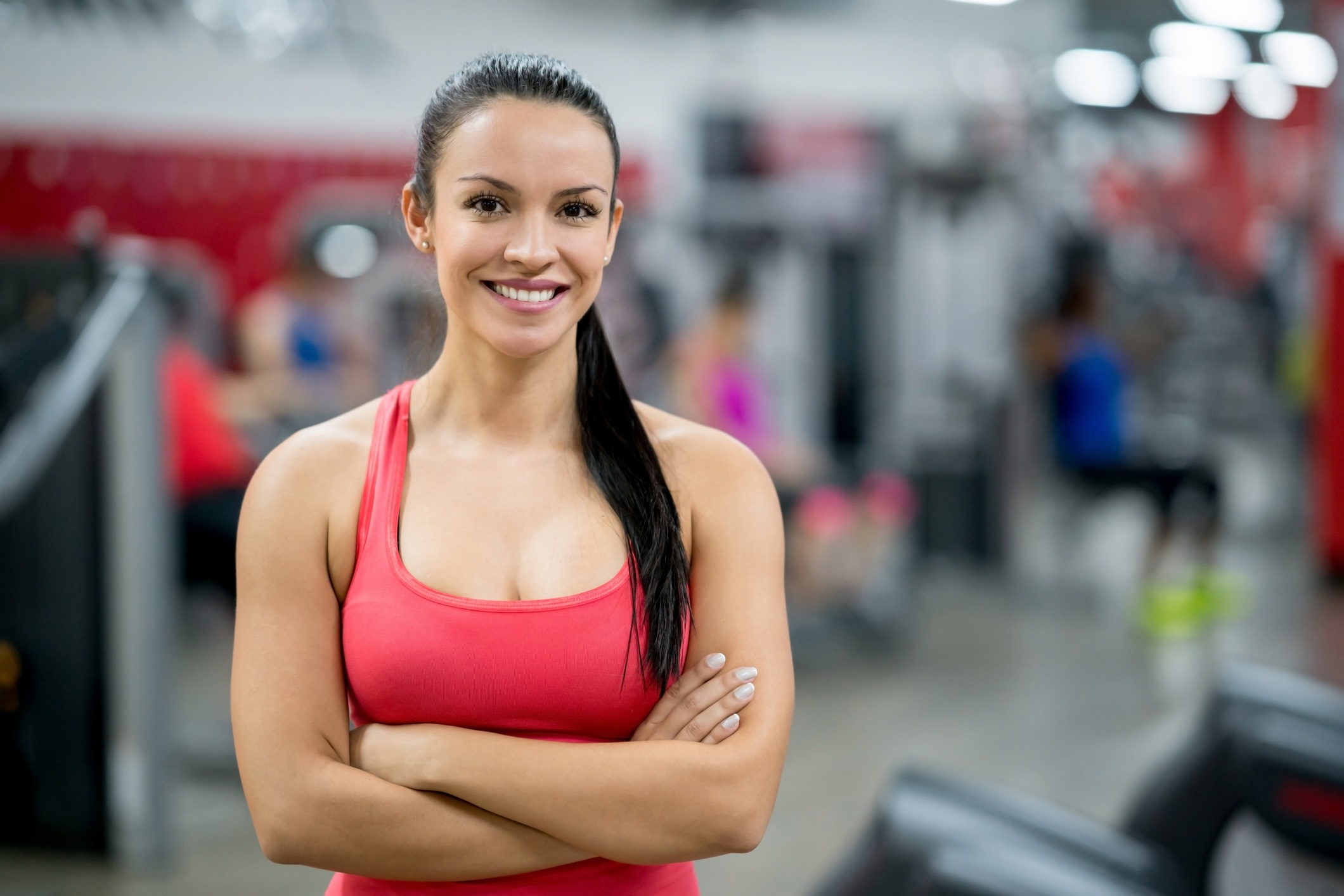 Fitness trainer standing by workout equipment